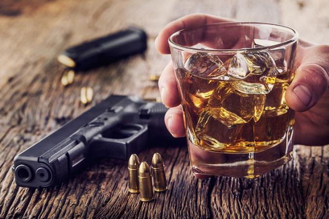 handgun and alcohol in glass